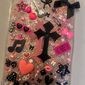 Può includere: Custodia trasparente per tablet decorata con glitter rosa, cuori, stelle, fiocchi e una croce nera. Include una chitarra in miniatura, occhiali da sole e un biglietto con la scritta "Lonely Hearts Club".