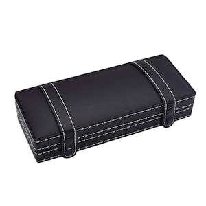 May include: A rectangular black box with white stitching and two white straps. The box has a leather-like texture and a clasp closure. The stitching is visible along the edges and straps, creating a decorative detail.