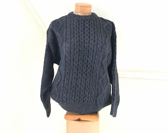 May include: A dark gray cable knit sweater with a crew neck.