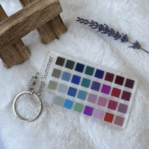 May include: A clear acrylic keychain with a silver keyring and clasp. The keychain features a color palette with the text "Deep Summer" and a variety of color swatches in shades of blue, green, purple, and red.
