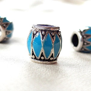 Peut inclure: Une perle ronde en argent et bleu turquoise avec un motif géométrique. La perle est lisse.