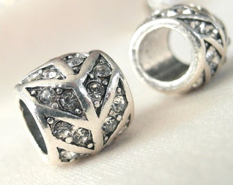May include: Two silver-toned metal bead spacers with clear rhinestone accents. The spacers are cylindrical with a hole in the centre. The rhinestones are arranged in a geometric pattern.