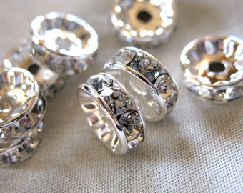 May include: Silver-toned metal bead caps with clear rhinestone accents. The bead caps have a round shape and a hole in the center for threading.