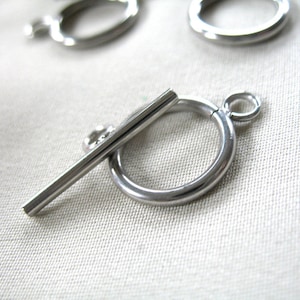May include: Silver-toned metal toggle clasp with a round ring and a straight bar. The clasp is designed for jewelry making or other craft projects.