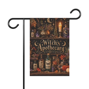Peut inclure: Un drapeau de jardin rectangulaire suspendu à un support en métal noir, portant le texte Witch's Apothecary en lettres dorées. Le motif montre des étagères remplies de flacons en verre, un chaudron, une bougie allumée et des plantes.