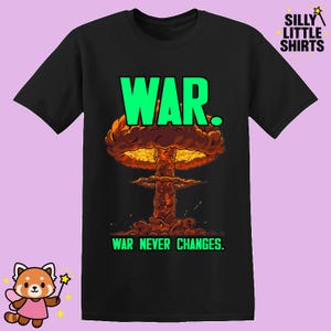 Könnte beinhalten: Schwarzes T-Shirt mit einer Grafik einer Atompilzexplosion. Das Wort "WAR" steht in Grün über der Explosion, und "WAR NEVER CHANGES" steht darunter. Das T-Shirt ist von "SILLY LITTLE SHIRTS."