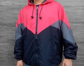 Puede incluir: Una chaqueta con capucha roja, negra y gris con cierre de cremallera. La chaqueta tiene un diseño de color contrastante con un patrón de chevron negro y gris en la parte delantera.