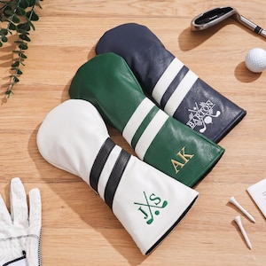 Könnte beinhalten: Drei Golfschlägerhauben in Weiß, Grün und Marineblau, jeweils mit zwei Streifen und personalisierter Stickerei. Die weiße Haube hat schwarze Streifen und den Text J S, die grüne hat weiße Streifen und AK, und die marineblaue hat weiße Streifen und BARTON.