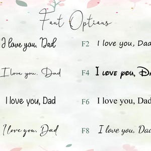 May include: Image showcasing eight font options for the phrase "I love you, Dad." The fonts vary in style, from elegant cursive to a bold, playful Disney-inspired font. The text is displayed on a soft, watercolor-like background with floral accents.