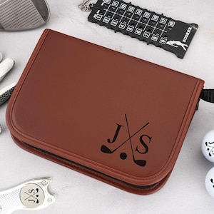 Pode incluir: Uma bolsa de acess&oacute;rios de golfe em couro castanho com z&iacute;per e al&ccedil;a pretos. A bolsa &eacute; personalizada com as iniciais "J S" e tacos de golfe cruzados. Bolas de golfe, um taco de golfe e um marcador de pontua&ccedil;&atilde;o tamb&eacute;m s&atilde;o vis&iacute;veis.