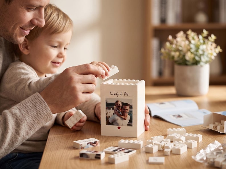 May include: A white Lego-style block container with a photo and the text "Daddy & Me". The container is being assembled with white Lego bricks. A photo of a father and child is on the front, with a small red heart below.
