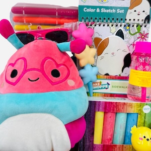 May include: A gift set with a plush toy, sunglasses, markers, a coloring book, sidewalk chalk, and a bubble bottle. The plush toy is pink, blue, and white, with heart-shaped glasses. The set includes a Color & Sketch Set.