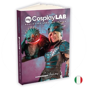 Può includere: Un libro intitolato "my Cosplay LAB REALIZZARE ARMATURE IN FOAM" presenta una donna in armatura cosplay che tiene in mano un pupazzo a forma di drago. La copertina è viola con testo bianco e il titolo del libro. La bandiera italiana è in basso a destra.