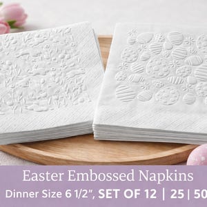 May include: Two stacks of white embossed Easter napkins, 6.5 inches square, on a wooden tray. One stack features a floral and bunny design, the other has an egg pattern. Pink and blue Easter eggs are in the foreground. The napkins are labeled "Easter Embossed Napkins".