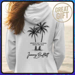 May include: White hooded sweatshirt with a palm tree graphic and the text "Wrinkles Only Go Where Smiles Have Been" and "Jimmy Buffett". A "Great Gift" sticker is in the upper right corner.