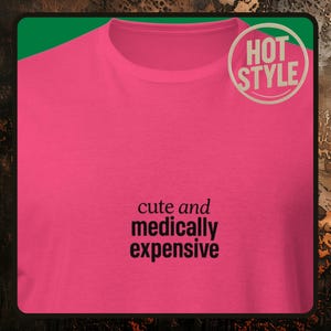 May include: A bright pink t-shirt with the text "cute and medically expensive" in black. A circular "HOT STYLE" sticker is in the upper right corner. The shirt is a crew neck style.