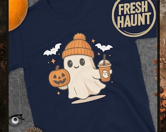 Puede incluir: Camiseta azul marino con un fantasma de dibujos animados que lleva un gorro naranja y sostiene una calabaza y una bebida. El fantasma está rodeado de murciélagos y estrellas. La camiseta tiene el texto "FRESH HAUNT" en un diseño circular.