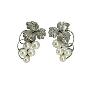 May include: A pair of silver earrings with a grape cluster design. Each earring features a cluster of white pearls and a silver leaf design.