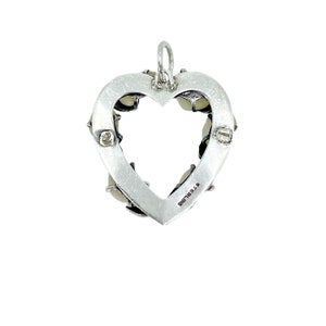 Op de afbeelding: Een zilveren hartvormige hanger met een witte stenen rand en het woord "STERLING" gegraveerd op de achterkant.