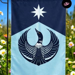 May include: A garden flag featuring a stylized design. The top section is navy blue, with a white star. Below, a light blue section displays a black and white bird with outstretched wings. The flag is hanging outdoors.