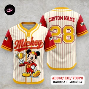 May include: Cream-colored baseball jersey with red and yellow accents. Features a cartoon Mickey Mouse graphic holding a trophy, the name "Mickey", and the number 28. The back has "CUSTOM NAME" and the number 28. The sleeves have checkered flags. Text at the bottom reads "ADULT/ KID/ YOUTH BASEBALL JERSY".