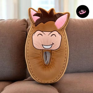 A brown plush toy resembling a horse is sitting on a couch.