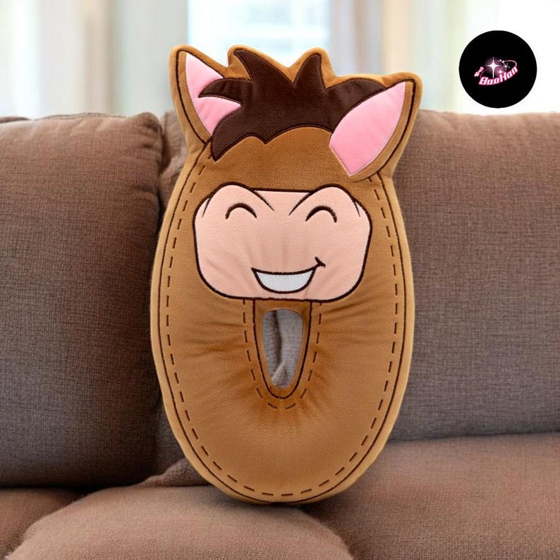 A brown plush toy resembling a horse is sitting on a couch.