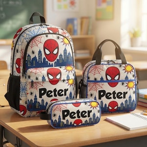 A Spiderman-themed backpack, a lunch bag, and a pencil case are displayed on a desk in a classroom setting.