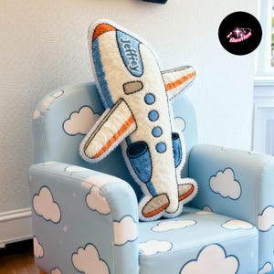 A blue chair with a cloud-shaped airplane pillow on it.