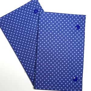 May include: Two rectangular fabric covers featuring a dark blue background with a repeating pattern of small light blue polka dots. Each cover is constructed with stitched edges and includes a single dark blue plastic snap fastener for closure.