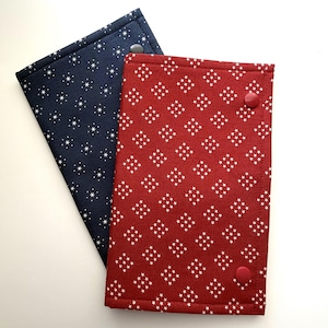 May include: Two fabric cases, one navy blue with white star patterns and the other red with white star clusters. Each case has a button closure. The cases are likely designed for storing small items or as protective covers.