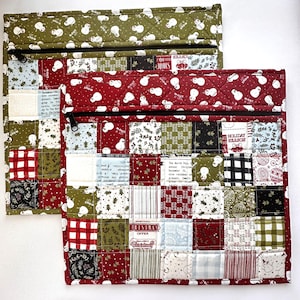 May include: Two quilted Christmas-themed pouches. The top portion of each pouch features a repeating snowman pattern on a green or red background. The lower sections are patchwork with various holiday-themed fabrics. Each pouch has a black zipper.