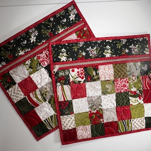 Puede incluir: Dos bolsas de cremallera acolchadas de color rojo y verde con un diseño de patchwork. Las bolsas tienen un fondo blanco con cuadrados rojos, verdes y blancos. Los tiradores de las cremalleras son plateados.
