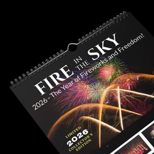 May include: A black spiral-bound calendar titled "FIRE IN THE SKY" with fireworks imagery. The calendar is a 2026 collector's edition, featuring the text "The Year of Fireworks and Freedom!"