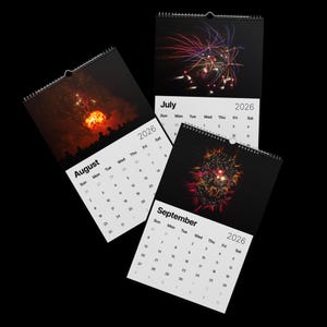 May include: Three wall calendars for 2026, each featuring a different firework display against a black background. Months include August, July, and September. The calendars have a spiral binding at the top.