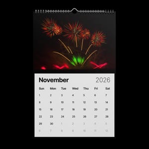 May include: A spiral-bound wall calendar for November 2026, featuring a vibrant fireworks display against a dark background. The calendar grid displays the days of the week and dates, with the month's name and year prominently displayed.