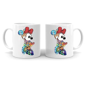 Puede incluir: Dos tazas de cer&aacute;mica blanca con un dise&ntilde;o colorido de Minnie Mouse. El dise&ntilde;o es un mosaico de varios personajes y escenas, con un lazo rojo y una cara sonriente. Las tazas son ideales para caf&eacute; o t&eacute;.
