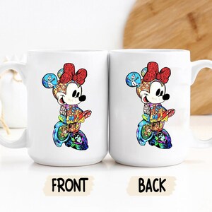 Puede incluir: Dos tazas de cer&aacute;mica blanca con un dise&ntilde;o colorido de Minnie Mouse. El dise&ntilde;o presenta a Minnie Mouse con un lazo rojo y un patr&oacute;n colorido. La palabra "FRONT" est&aacute; impresa en una taza y "BACK" en la otra.
