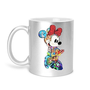 Puede incluir: Una taza de cer&aacute;mica plateada con un colorido dise&ntilde;o de Minnie Mouse. El dise&ntilde;o incorpora varios personajes de Disney y un lazo rojo. La taza tiene un asa blanca y un acabado brillante, adecuada para bebidas fr&iacute;as o calientes.