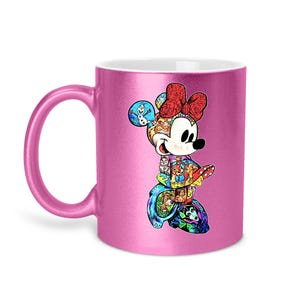 Puede incluir: Taza de cer&aacute;mica rosa con un dise&ntilde;o colorido de Minnie Mouse. El dise&ntilde;o incluye un lazo rojo y un collage de personajes de Disney. La taza tiene un acabado met&aacute;lico y un asa curva.