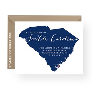 May include: A white card with a blue outline of the state of South Carolina. The text "We've moved to South Carolina" is written in cursive script. The text "The Anderson Family, 123 Middle Street, Mount Pleasant, SC 29464" is written in black below the state outline.