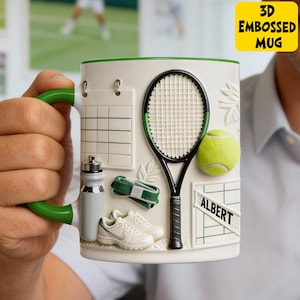 May include: A white ceramic mug with green accents and a 3D embossed tennis theme. Features a tennis racket, ball, shoes, water bottle, and the text "ALBERT". The mug has the text "3D EMBOSSED MUG" in a yellow box.