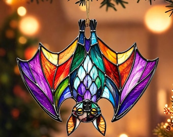 May include: A hanging ornament shaped like a bat with a stained glass appearance. The wings and body feature a vibrant, multi-colored pattern including shades of purple, blue, green, orange, and yellow, all outlined in thick black lines.