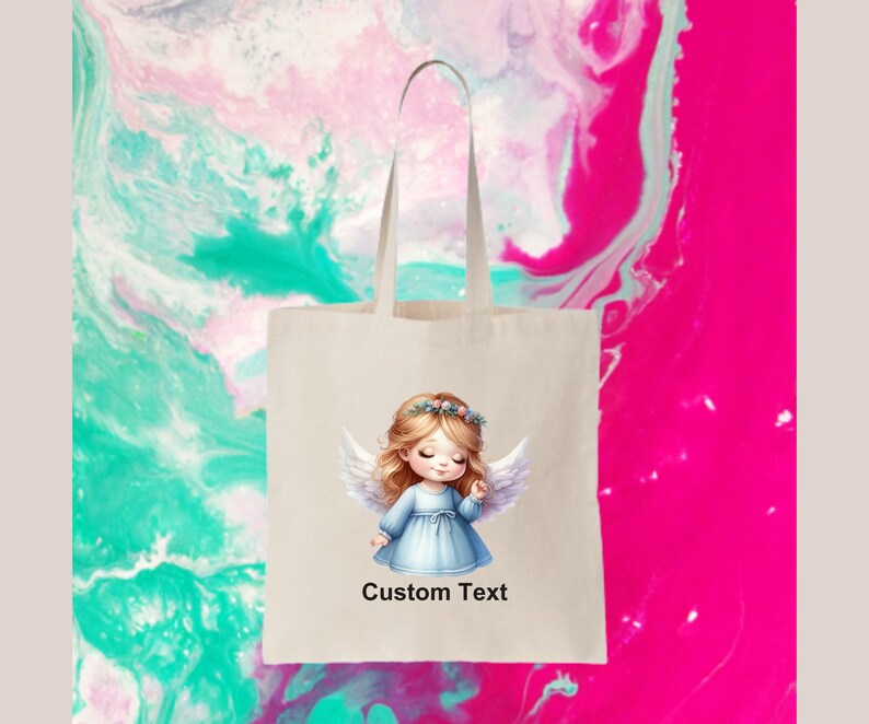 Puede incluir: Una bolsa de tela blanca con un lindo &aacute;ngel de dibujos animados con cabello rubio y alas azules. La bolsa tiene el texto "Custom Text" impreso en la parte delantera.