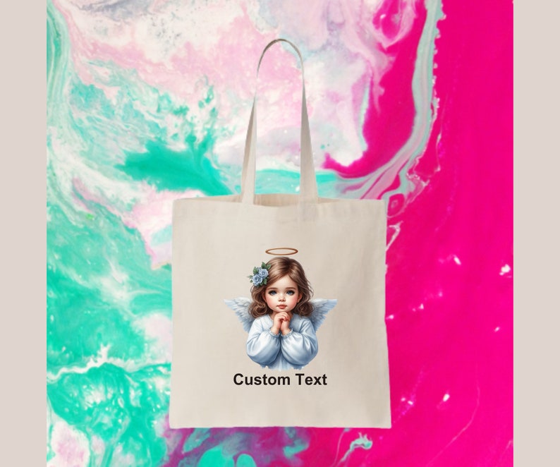 Pode incluir: Uma bolsa de tecido branca com uma imagem impressa de um anjo com uma aur&eacute;ola e flores azuis no cabelo. O anjo est&aacute; vestindo um vestido branco e tem as m&atilde;os juntas em ora&ccedil;&atilde;o. O texto "Custom Text" est&aacute; impresso abaixo da imagem.