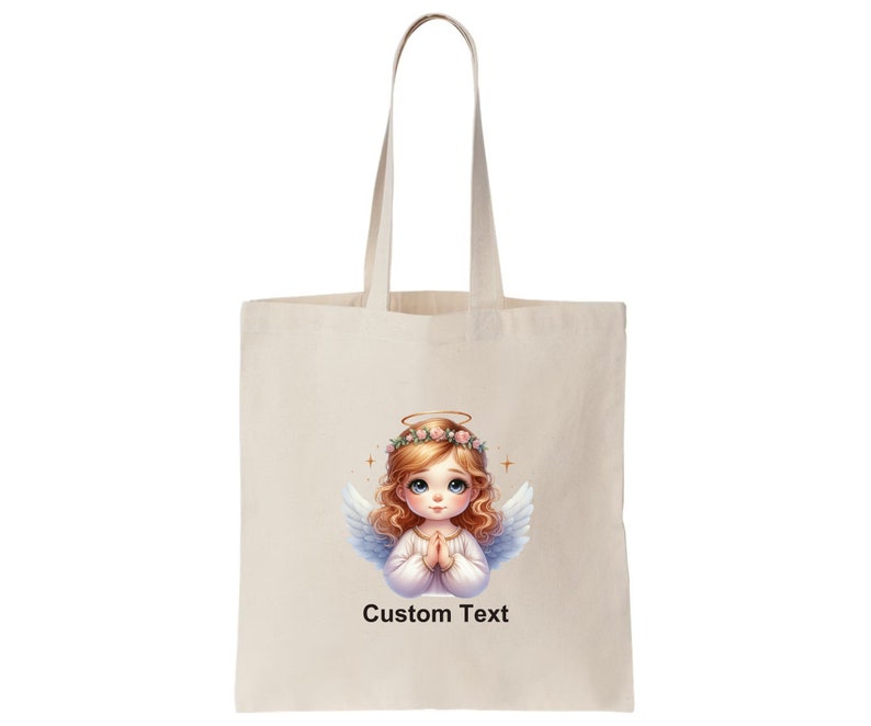 May include: A white tote bag with a design of a cute angel with blonde hair and a halo. The angel is wearing a white dress and has her hands clasped in prayer. The text "Custom Text" is printed below the angel.