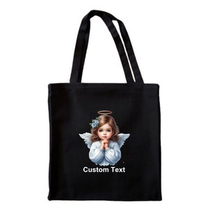 Pode incluir: Sacola de tecido preta com um anjo branco com halo e flores azuis no cabelo. O anjo est&aacute; com as m&atilde;os juntas em ora&ccedil;&atilde;o. O texto "Custom Text" est&aacute; impresso abaixo do anjo.