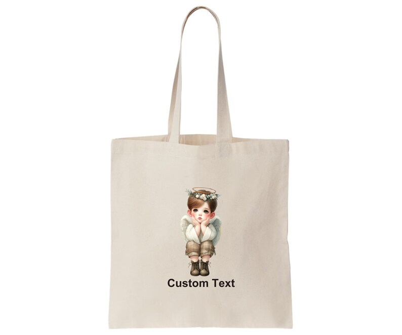 May include: A white tote bag with a design of a young angel with a halo and a flower crown. The angel is wearing a white shirt and brown pants. The text "Custom Text" is printed below the image.