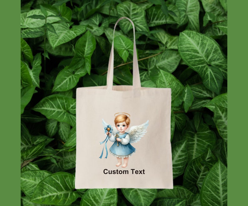 以下が含まれることがあります： 白いトートバッグに、青と白の天使のイラストと「Custom Text」の文字が書かれています。