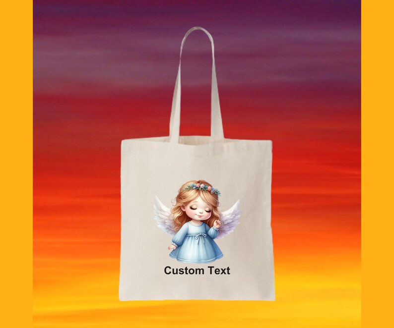 Puede incluir: Una bolsa de tela blanca con un dise&ntilde;o de una ni&ntilde;a &aacute;ngel con alas y una corona de flores. El texto "Custom Text" est&aacute; impreso en la bolsa.